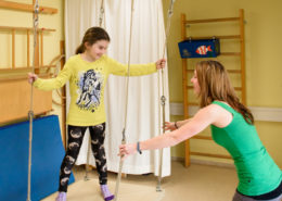 Kind auf Schaukel mit Therapeutin